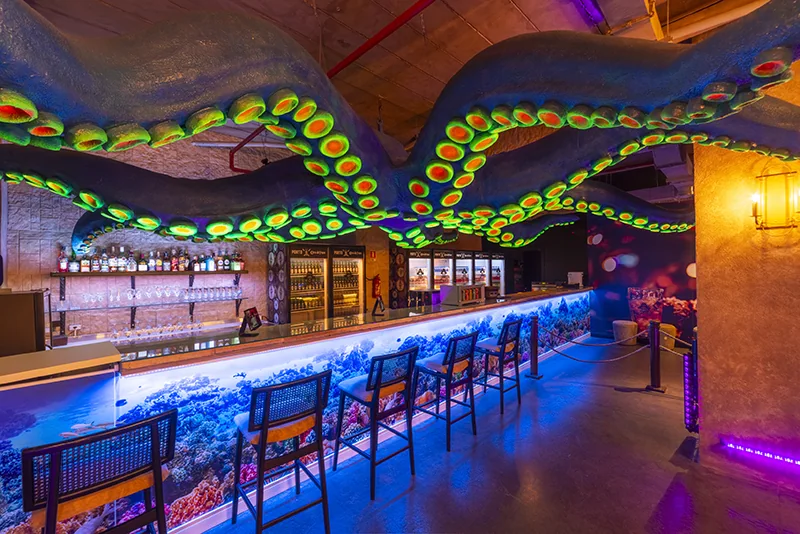 Balcão do bar com iluminação azul e decoração temática